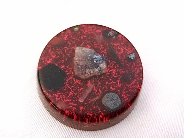 Red Root Chakra orgone disc with black tourmaline, hematite and shungite on a yellow cloth