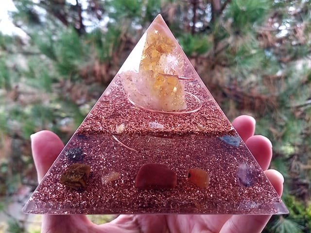 Abundance orgone energy pyramid in front of a pine tree.