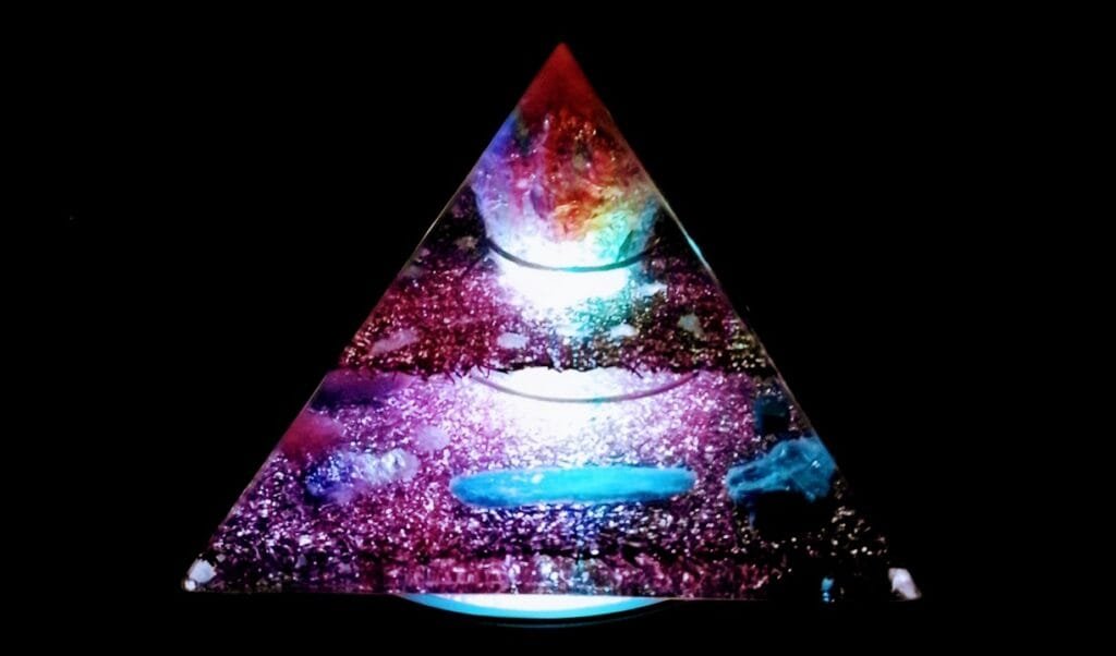 Abundance Orgone Pyramid, glowing, on top of an led light stand