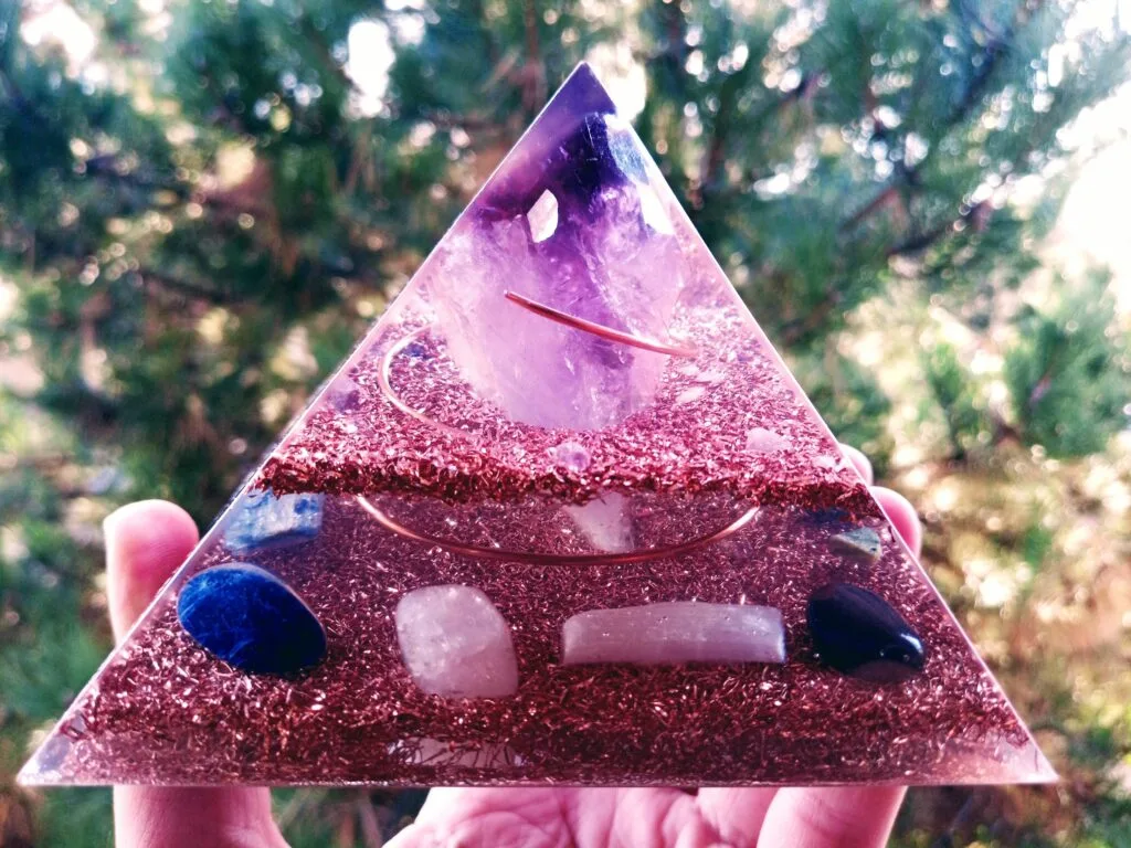 Amethyst orgone pyramid with large amethyst point in front of a tree