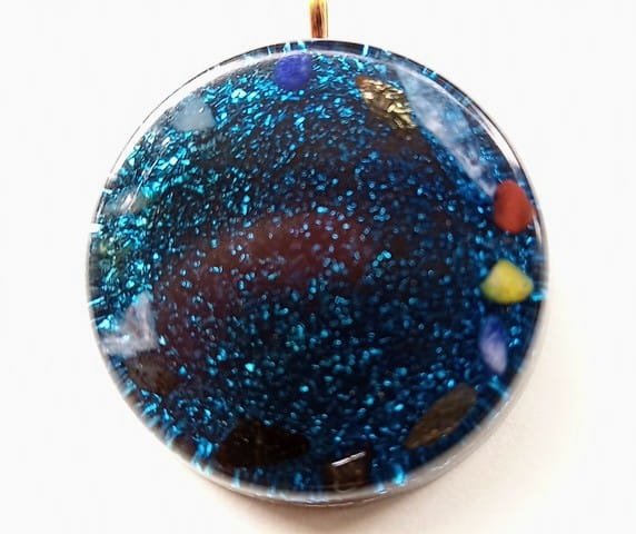 Blue flower of life orgone pendant on a white cloth.