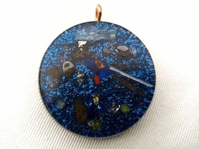 Blue orgone pendant with crystals a on white cloth