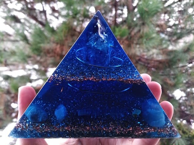 Blue orgone pyramid with amethyst point at the top and blue calcite crystal