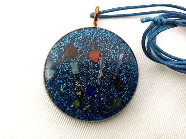 Blue orgone pendant with blue string on white cloth