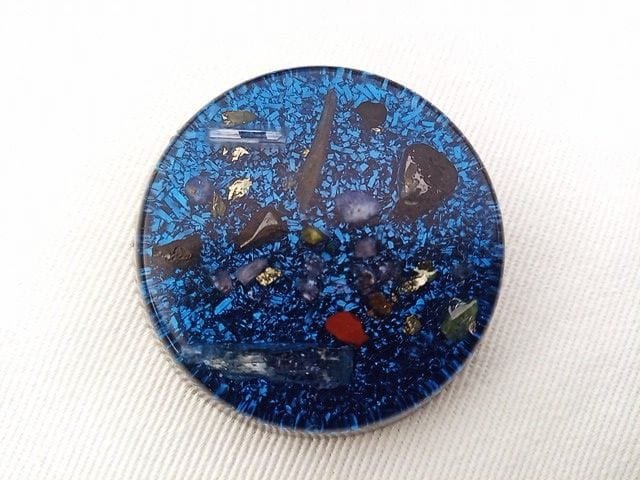 Blue orgone pocket disc on a white cloth.