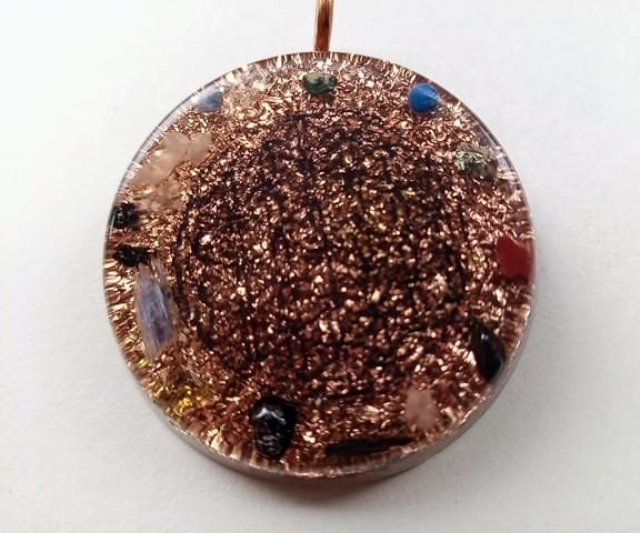 Clear Flower of Life orgone pendant with healing crystals on a white background.