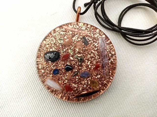 Clear orgonite pendant with black string on white cloth