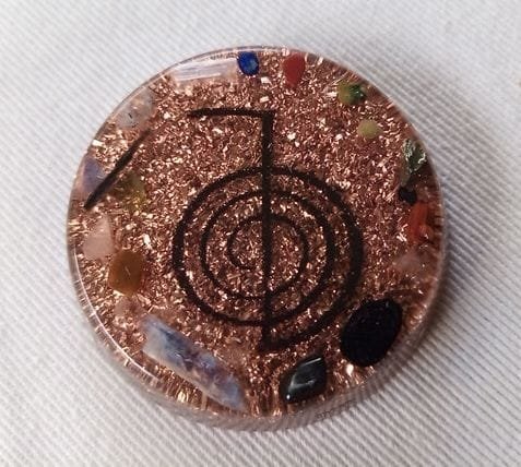 Clear reiki orgone pocket disc with amethyst and selenite crystals on a white cloth.