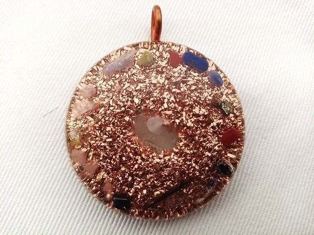 Clear tasmanian energy vortex orgone pendant with clear quartz crystal on white cloth