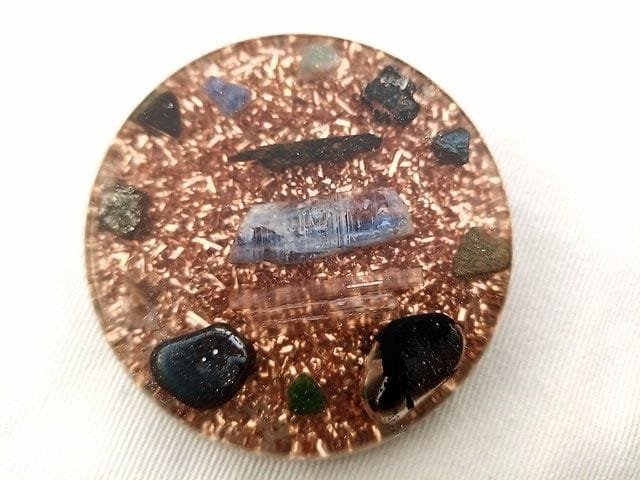 EMF orgone disc with crystals for protection on a white cloth.