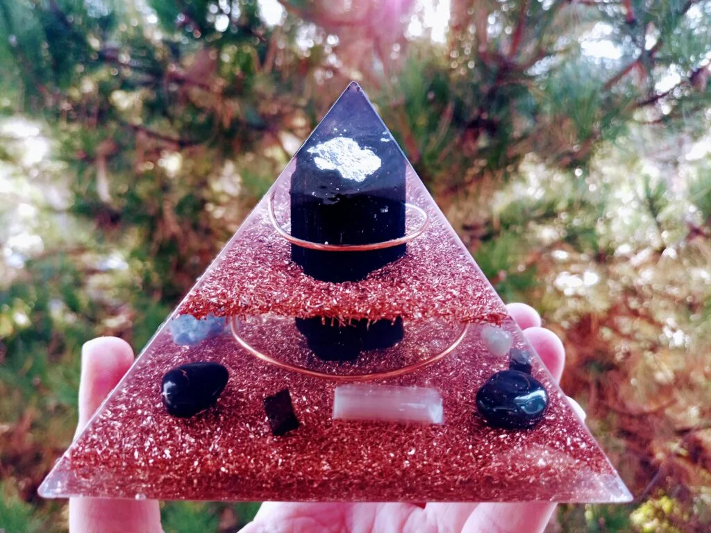 EMF orgonite pyramid with black tourmaline at the top, in front of a tree