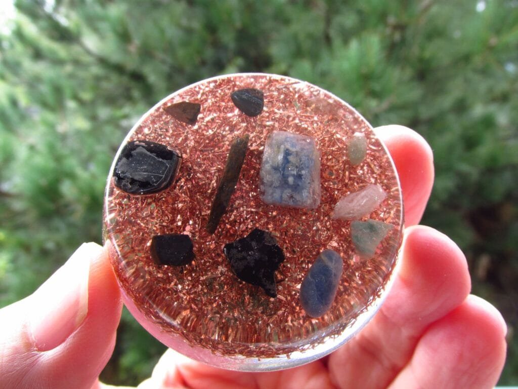 EMF orgonite disc held up in front of a tree.