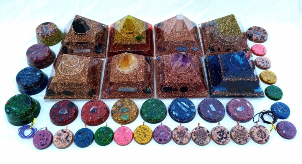 orgonite energy pyramids with orgone pendants discs and puck generators with amethyst selenite rose quartz crystals