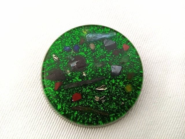 Green orgone pocket disc on a white cloth.