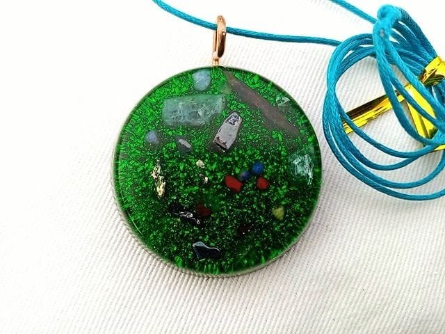 Green orgonite pendant with turquoise string on white cloth