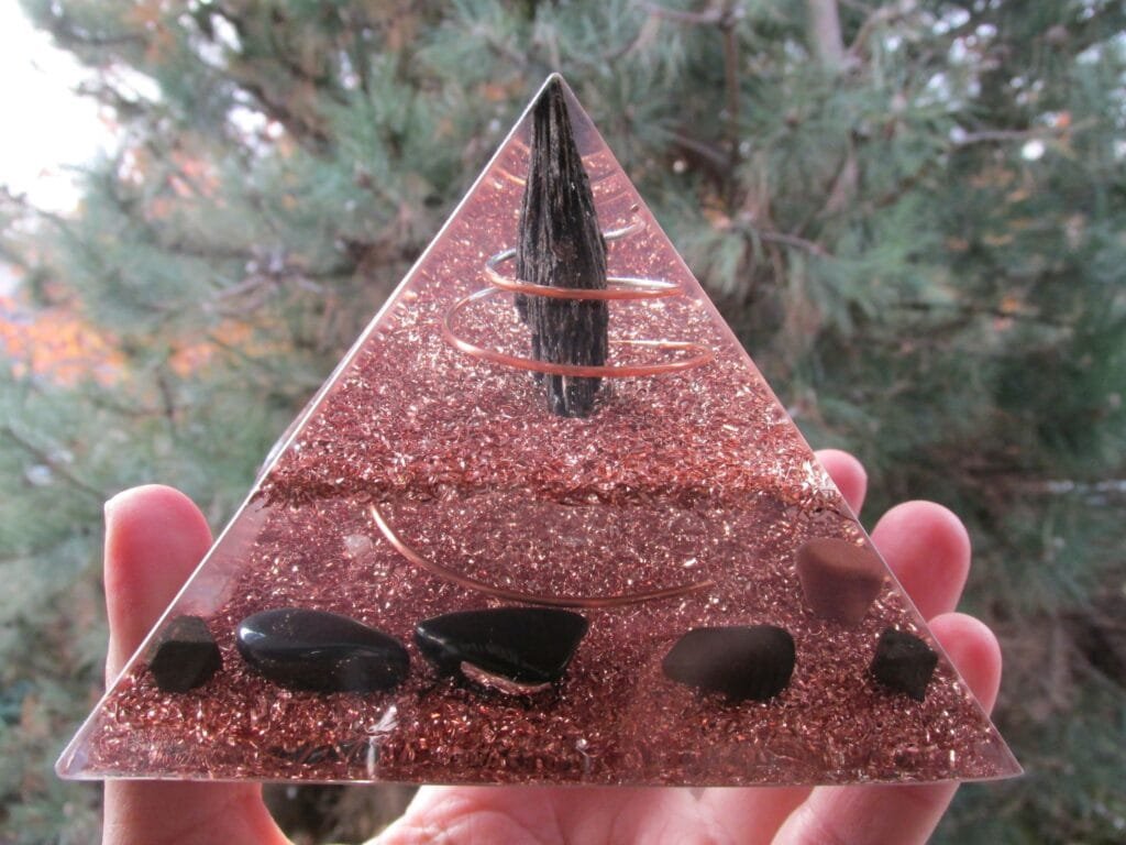 Grounding Orgonite Pyramid with black tourmaline and shungite in front of a pine tree.