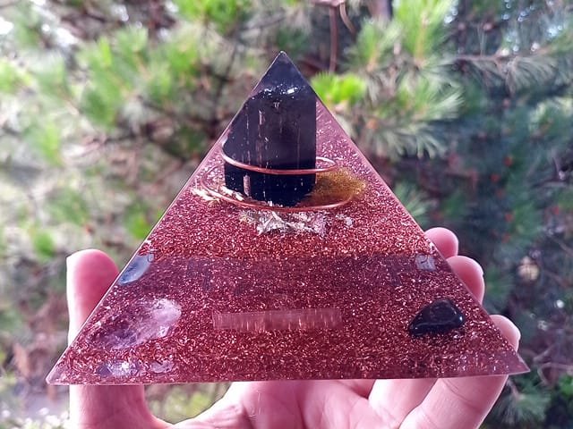 Immunity orgone energy pyramid with clear resin and copper in front of a tree.