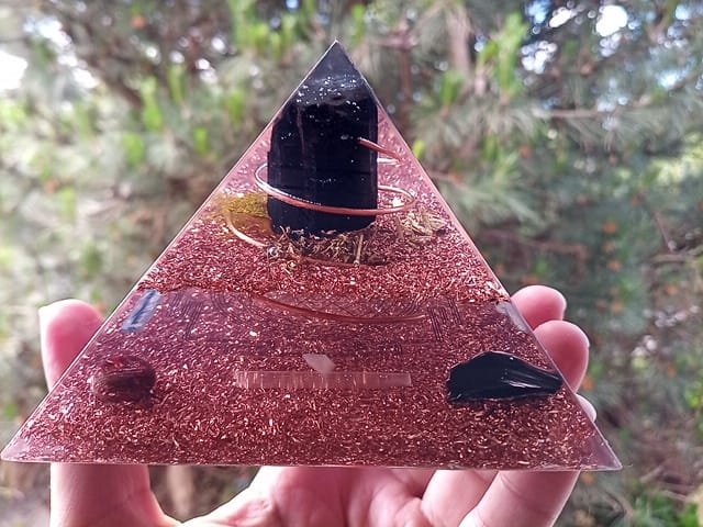 Immunity orgone energy pyramid with clear resin and copper in front of tree.