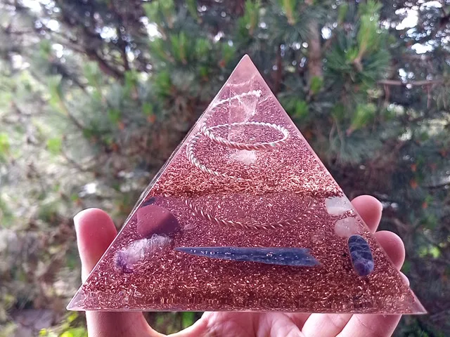 Lemurian Seed Crystal orgone pyramid with blue kyanite in front of a tree.