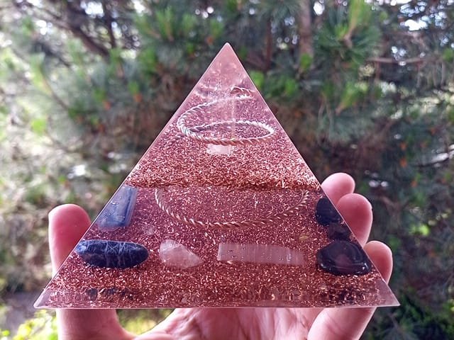 Lemurian Seed Crystal orgone pyramid with crystals in front of a pine tree.