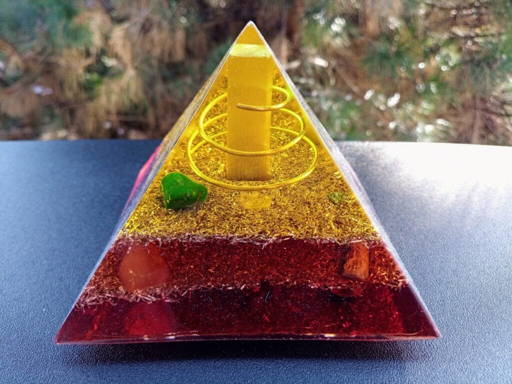 Lower Chakra orgone energy pyramid on a black table in front of a tree.