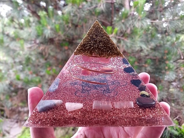 Metatron's Cube Orgone Pyramid with selenite and rose quartz crystals in front of a tree.