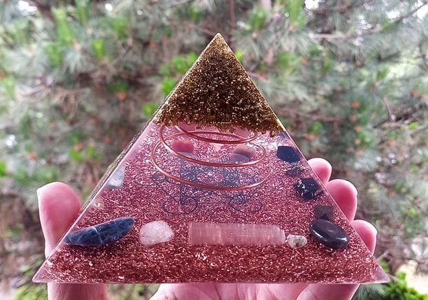 Metatron's Cube Orgone Pyramid with brass on top and copper on bottom in front of tree.