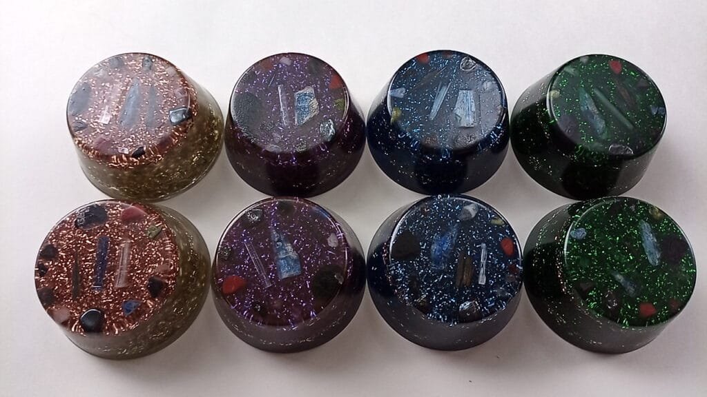 Eight orgone pucks in clear, violet, blue and green on a white background