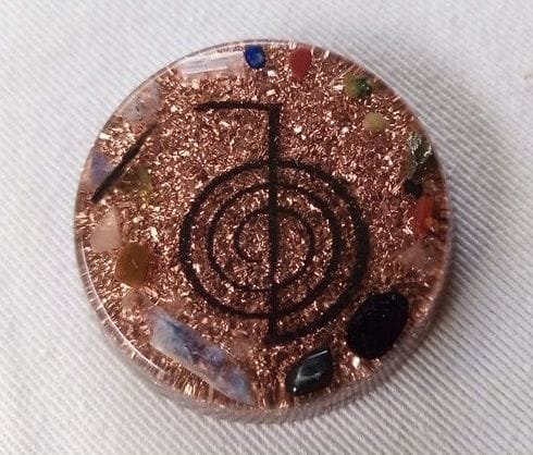 Clear reiki orgone pocket disc with black tourmaline and shugite crystals on a white cloth.