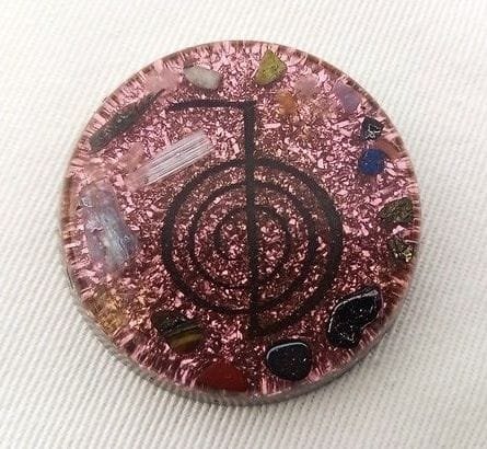 Reiki orgone pocket disc with amethyst and selenite crystals on a white cloth.