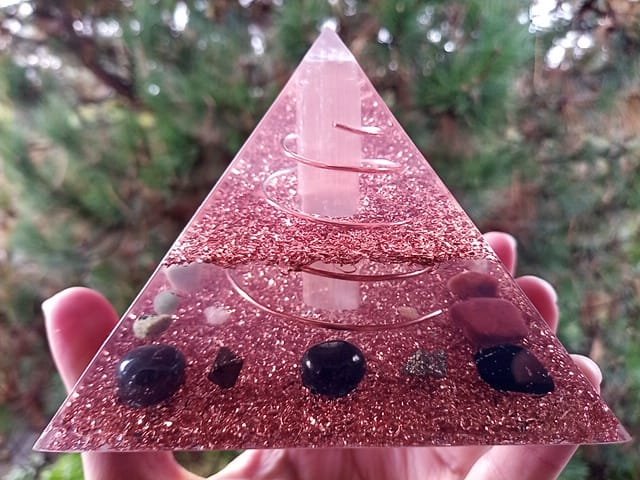 Selenite orgone energy pyramid, with shungite and black tourmaline in front of a tree.