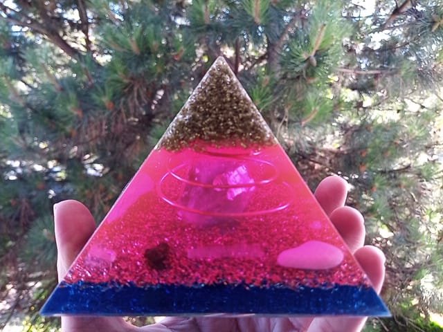 St. Germain orgone energy generator with chakra crystals being held in front of tree.