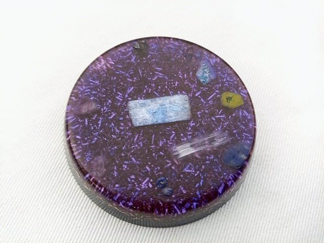 Indigo colored Third Eye Chakra Orgone Disc on a white cloth.