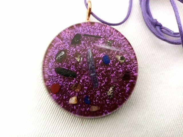 Violet orgonite pendant with violet string on white cloth