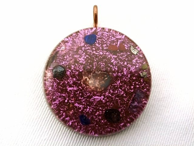 Violet tasmanian energy vortex orgone pendant with amethyst crystals on white cloth