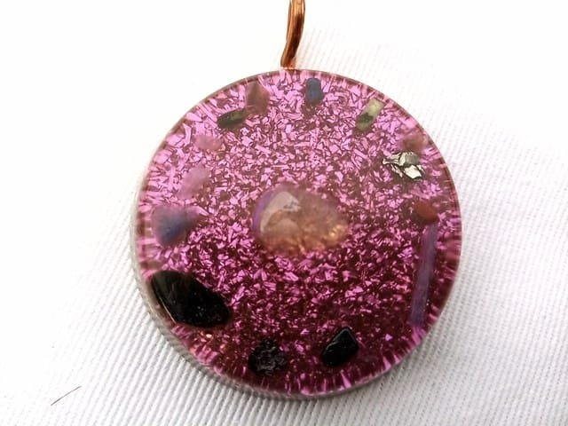 Violet tasmanian energy vortex orgone pendant with selenite crystal on white cloth