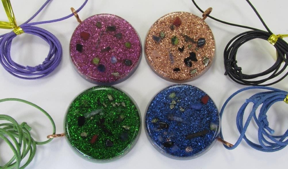 Standard Orgone pendants in violet, clear, green and blue on white background