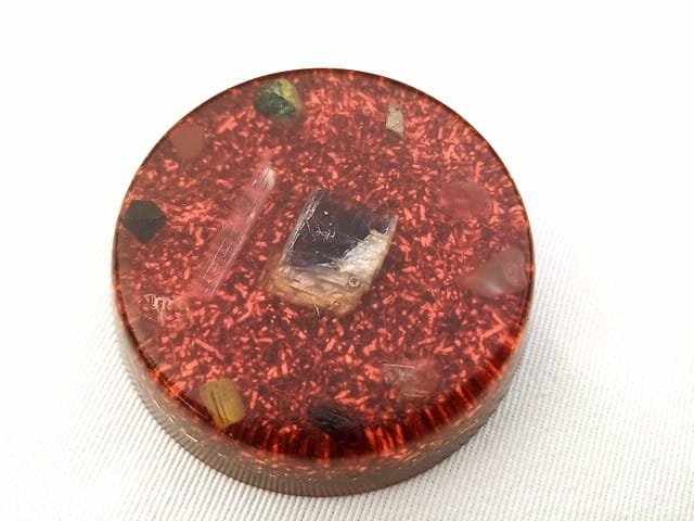 Orange Sacral Chakra orgonite disc with sacral chakra crystals on a white cloth