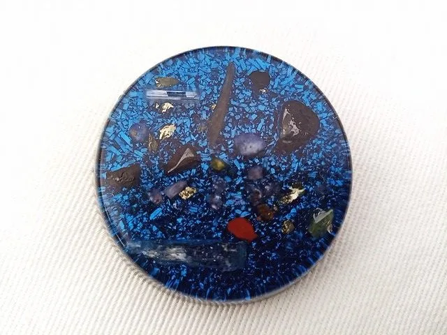 Blue orgone pocket disc on a white cloth.