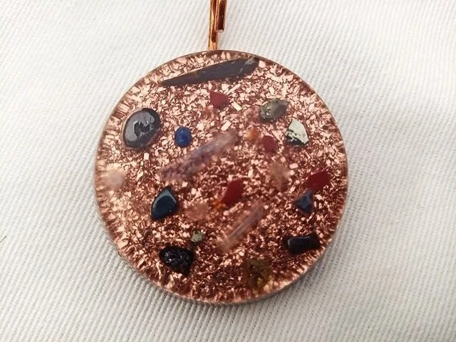 Clear orgone pendant with amethyst and selenite crystals on white cloth