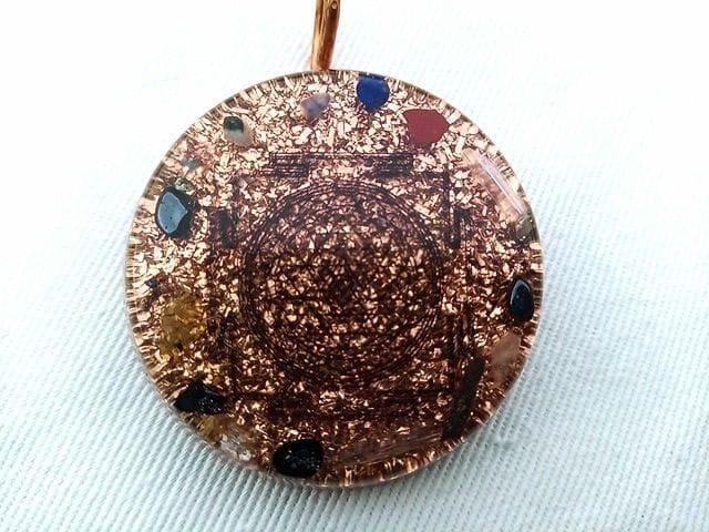 Clear Sri Yantra orgone pendant on a white cloth.