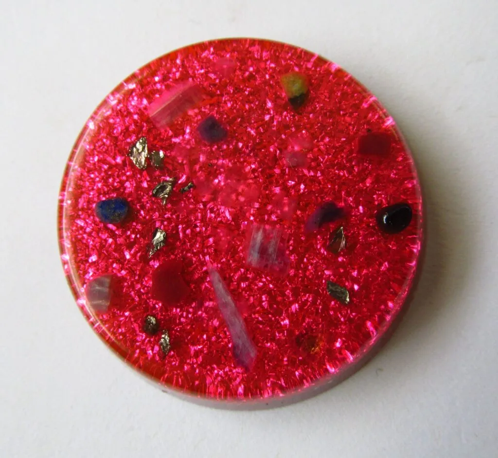 Pink Divine Love orgonite disc with love crystals on a white background