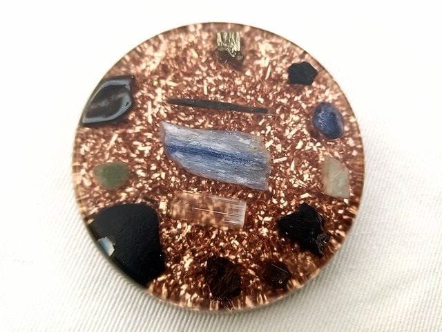 EMF orgone disc with coppper on a white cloth.