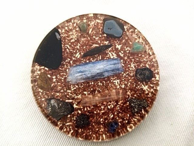 EMF orgone disc with shungite protection crystal on a white cloth.