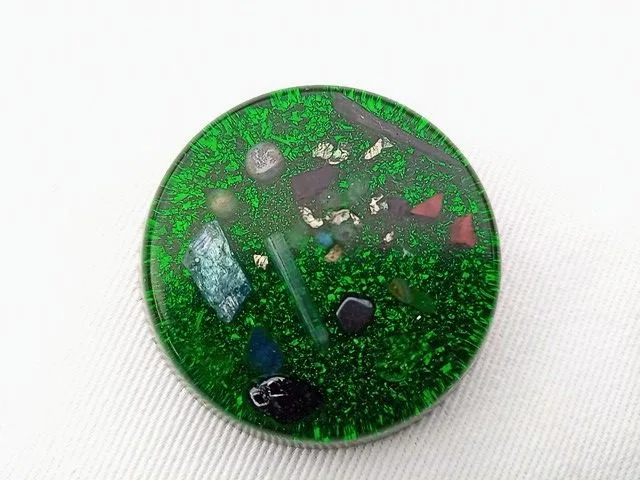 Green orgone pocket disc with blue kyanite and amethyst crystals on a white cloth.