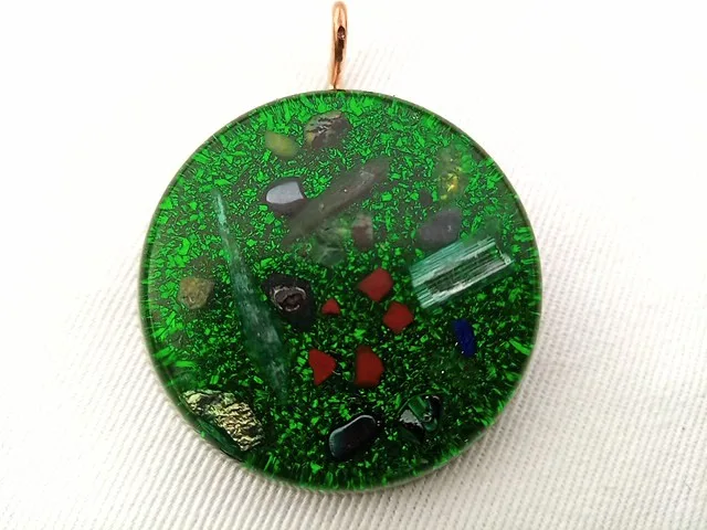 Green orgone pendant with crystals and a on white cloth