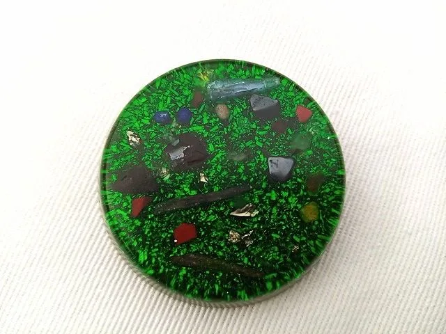 Green orgone pocket disc on a white cloth.
