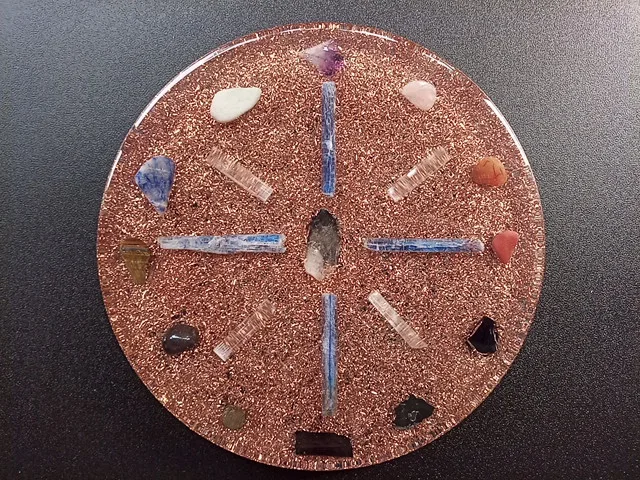 clear orgone plate with protection and grounding crystals on a black table.