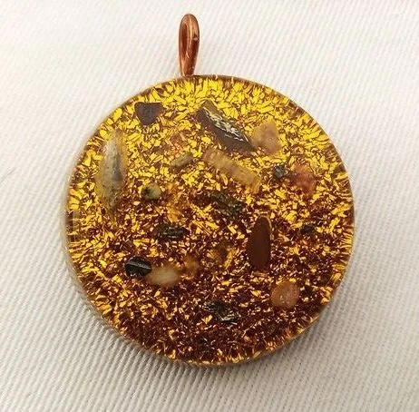 Yellow solar plexus chakra orgone pendant with clear quartz and citrine on white cloth.