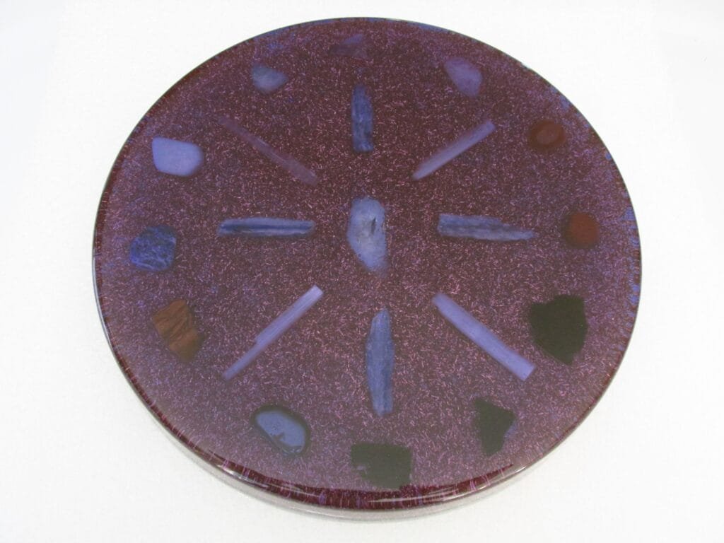 Violet charging and clearing orgone plate with clear quartz on a white cloth.